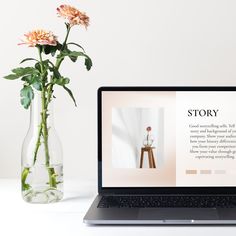 an open laptop computer sitting on top of a desk next to a vase with flowers