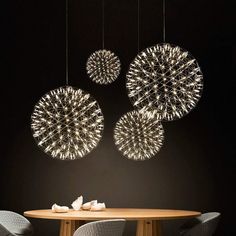 three circular lights hanging from the ceiling above a table with four chairs in front of it