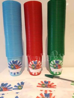 there are many different colored cups on the table with scissors and paper plates in front of them