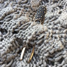 two hair clips laying on top of a gray knitted blanket next to each other