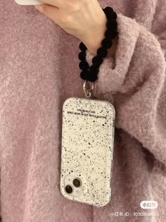 a person holding a cell phone and wearing a black beaded necklace with words written on it