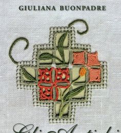 the cross is embroidered on top of a white cloth with red and green designs in it