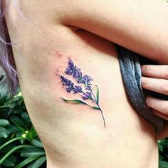 a woman's stomach with a small flower tattoo on her left side ribcage