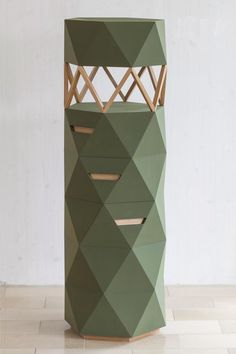 a green tower made out of cardboard sitting on top of a tiled floor next to a white wall