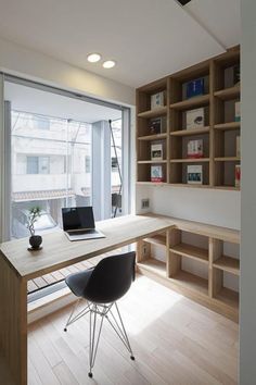 a desk with a laptop computer on it in front of a window and bookshelves