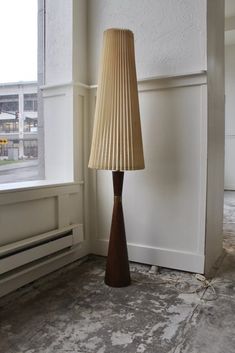 a lamp sitting next to a window in a room with white walls and flooring