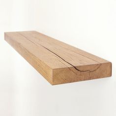 a close up of a wooden shelf against a white wall