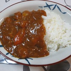 a white plate topped with rice and meat covered in gravy on top of a table