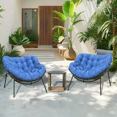 two blue chairs sitting on top of a white floor next to a table and potted plants