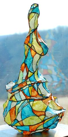 a colorful glass sculpture sitting on top of a wooden table next to a large window