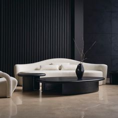 a modern living room with white couches and black table in the center, along with two chairs