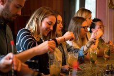 a group of people sitting at a bar making drinks