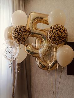 some balloons that are in the shape of numbers and leopard print on them, hanging from a wall