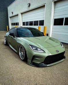 a green sports car parked in front of a garage