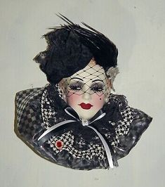 a doll with black hair and makeup on it's face is hanging from the wall