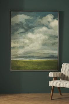 a painting hanging on the wall above a chair in front of a green painted wall