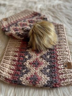 a knitted bag with a pom - pom sitting on top of it