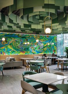 the interior of a restaurant with green, blue and yellow colors on the wall behind the tables