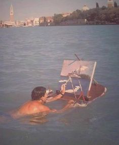 a man is in the water with an easel on his back and painting it