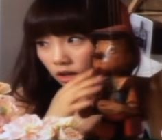 a woman holding a wooden doll in front of her face and looking at the camera