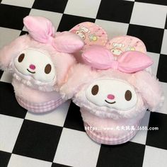 two pink slippers with bunny ears and bows are on a black and white checkered floor