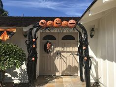 a house decorated for halloween with pumpkins on the front door and decorations hanging from the roof