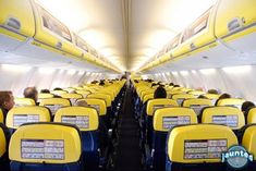 an airplane filled with lots of yellow seats and people sitting in the aisles looking at them