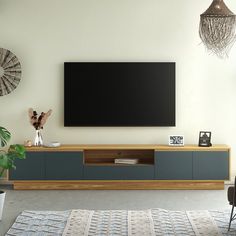 a large flat screen tv mounted to the side of a wooden entertainment center in a living room