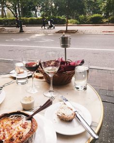 a table topped with plates and glasses of wine next to a basket filled with food