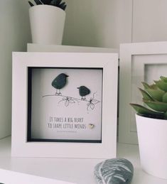 two birds sitting on top of a white shelf next to a potted succulent