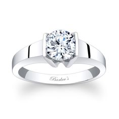 a white gold engagement ring with a round diamond in the center and an inscription on the side