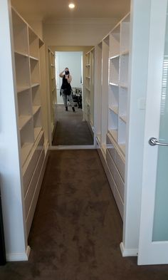 a woman taking a photo in the mirror of a walk - in closet with shelving