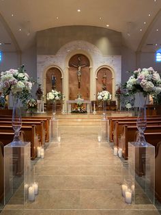 an empty church with candles and flowers on the pews