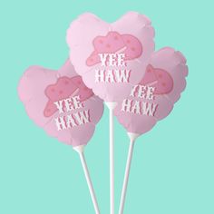 three pink heart shaped lollipops with the words yee haw on them