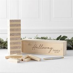 wooden blocks and pen sitting next to each other on a white surface with greenery in the background