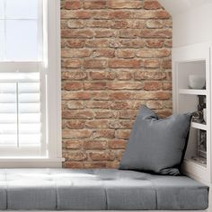 a window seat in front of a brick wall