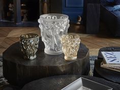 three glass vases sitting on top of a wooden table in front of a fireplace