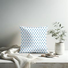 a white and blue pillow sitting on top of a table next to a potted plant