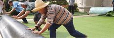 two men are bending over to pick up something off the ground while others look on