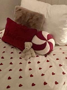 a teddy bear sitting on top of a bed next to two pillows and a pillow