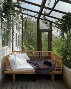 a bed sitting on top of a wooden floor next to a window filled with plants