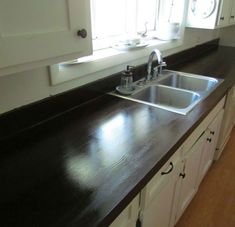 the kitchen counter is made of wood and has white cabinets with black trim on it