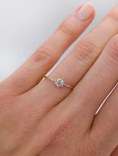 a woman's hand with a diamond ring on top of her finger and an engagement band