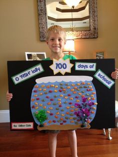 a young boy holding up a paper cut out of a fish tank