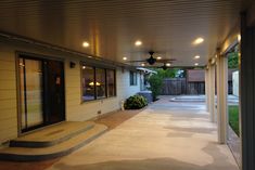 an empty covered patio with ceiling fans and steps leading up to the back door area