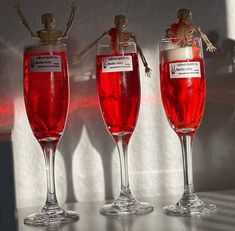 three wine glasses filled with red liquid sitting on top of a table next to each other