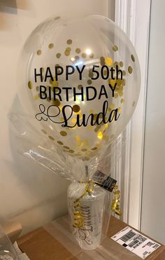 a balloon with the words happy 50th and some confetti on it sitting on a table