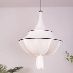 a white lamp hanging from the ceiling in a room with plants and potted plant