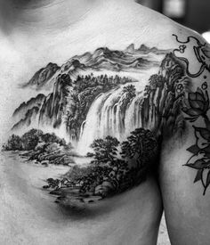 a man's chest with a mountain scene tattoo on his left arm and shoulder