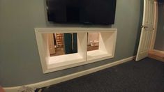 a flat screen tv mounted to the side of a wall next to a doorway in a room